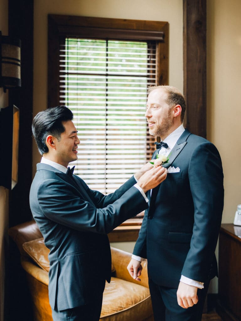 A groom in a tuxedo gets ready for a ceremony with best man help