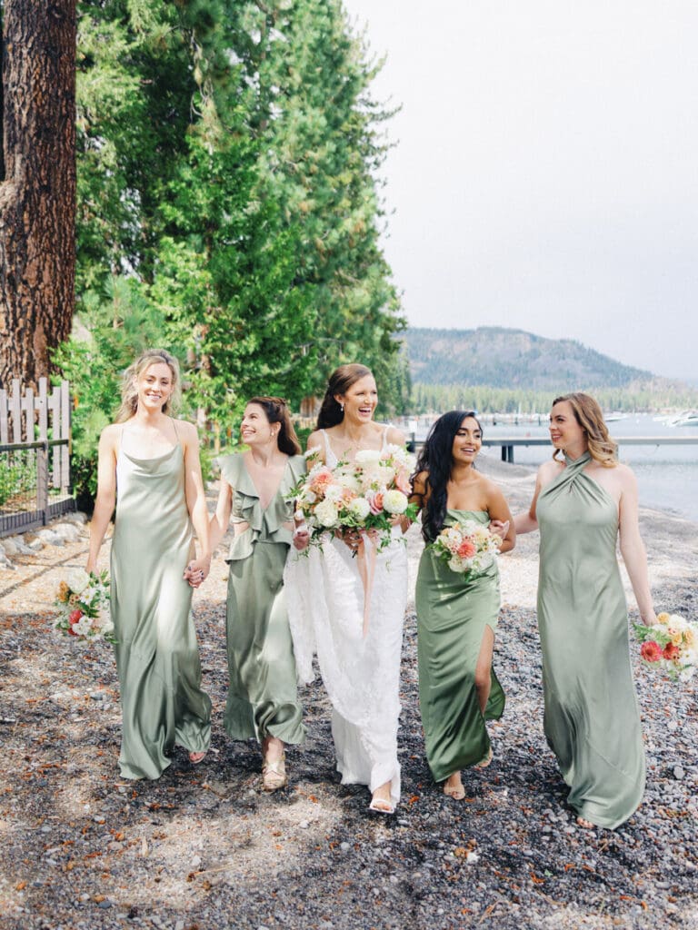 Bridesmaids walking and laughing on the beach at Edgewood Tahoe Resort wedding, highlighting the stunning backdrop of Lake Tahoe.