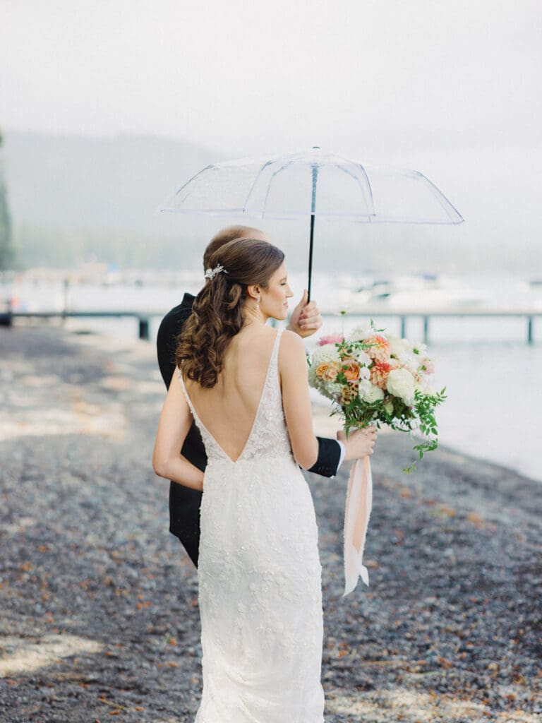 Rainy day Elegant bride and groom first look portraits on the beach at Edgewood Tahoe Resort wedding, highlighting the stunning backdrop of Lake Tahoe.