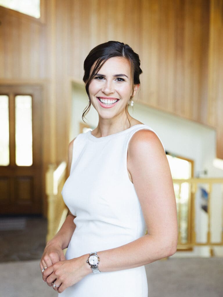 A smiling bride in a white dress poses for the camera at her wedding at Gar Woods, Lake Tahoe.