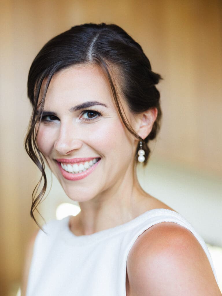 A smiling bride in a white dress poses for the camera at her wedding at Gar Woods, Lake Tahoe.