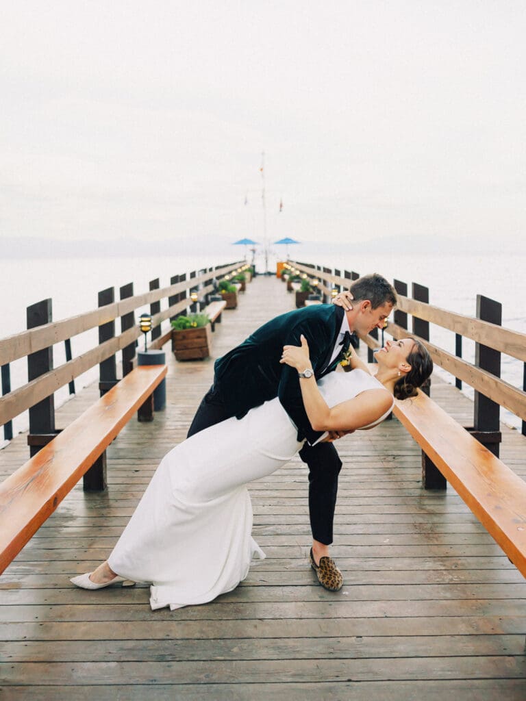 A bride and groom share a kiss on a picturesque pier at their Gar Woods Lake Tahoe wedding.