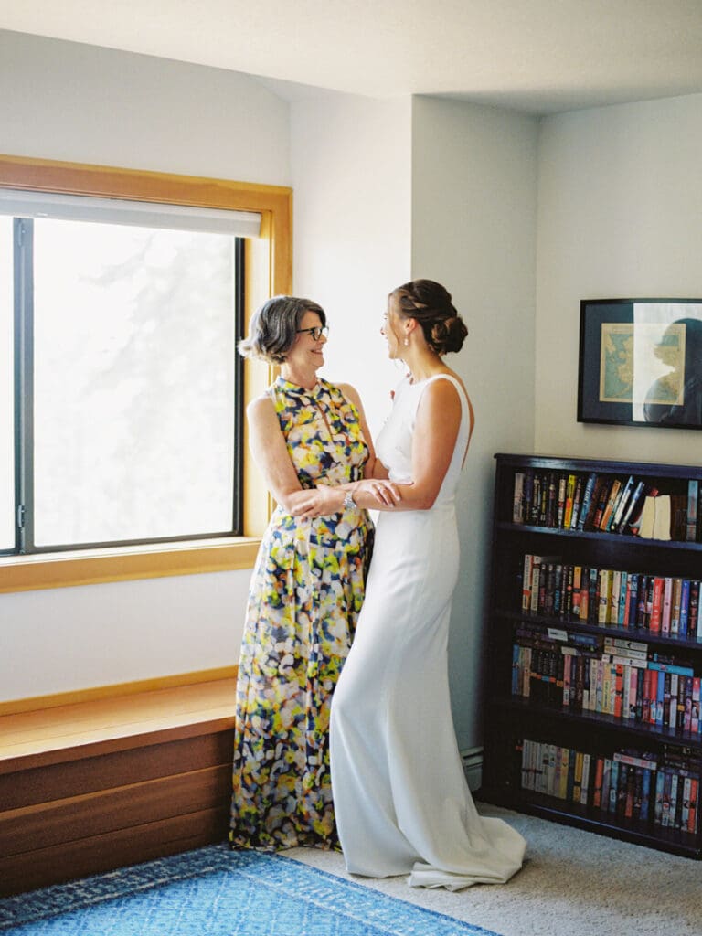 A touching scene of a mother and daughter sharing a moment and standing by a window whilst getting ready for Gar Woods Lake Tahoe wedding.