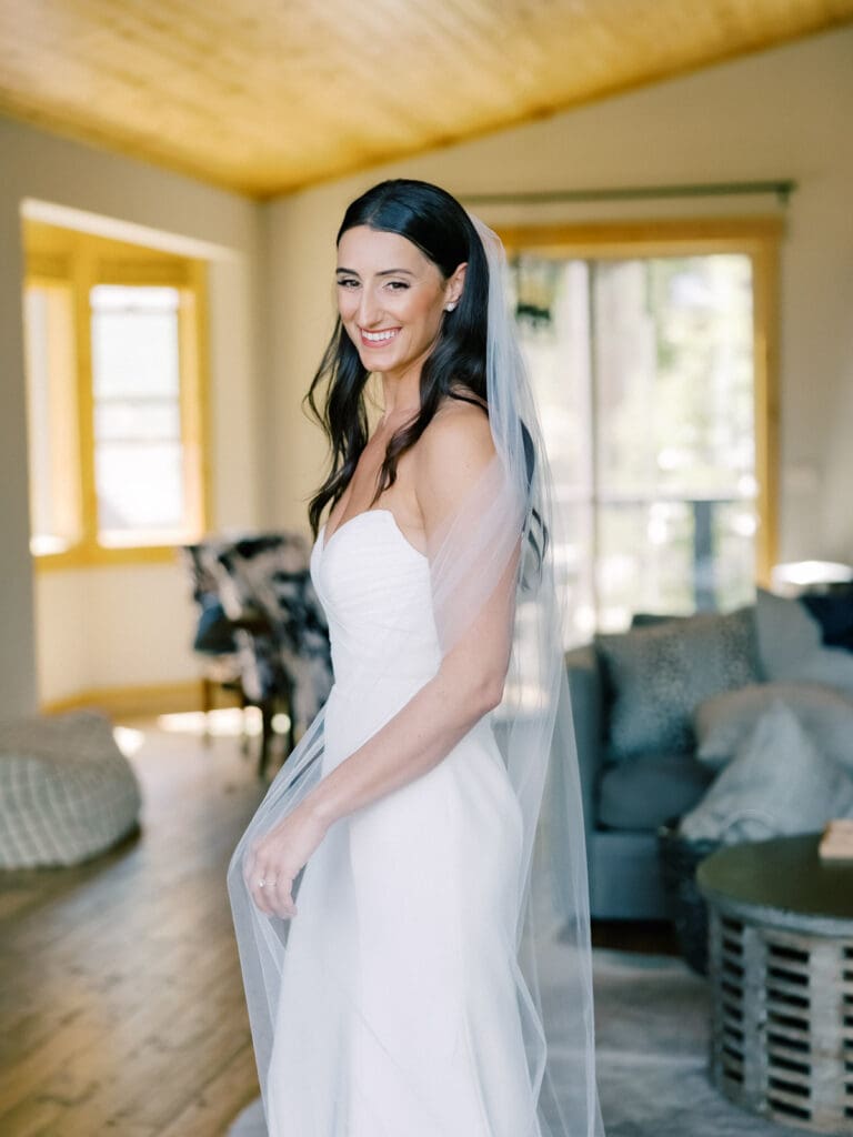 A beautiful bride in a white gown and veil poses gracefully at Gar Woods, Lake Tahoe, radiating joy.