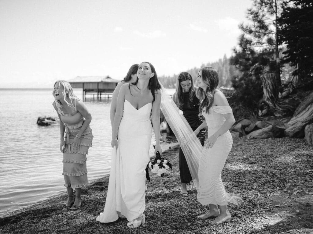 A stunning beach photo of bride and bridesmaids in blue dresses, radiating happiness at Gar Woods Lake Tahoe wedding.