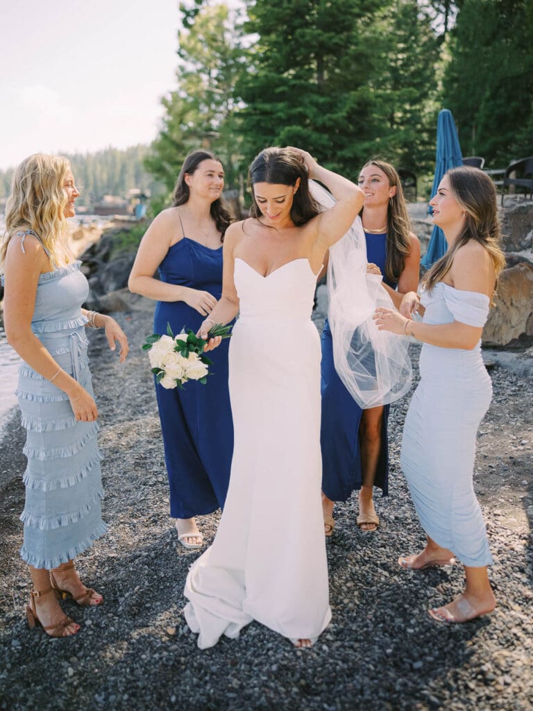 A stunning beach photo of bride and bridesmaids in blue dresses, radiating happiness at Gar Woods Lake Tahoe wedding.