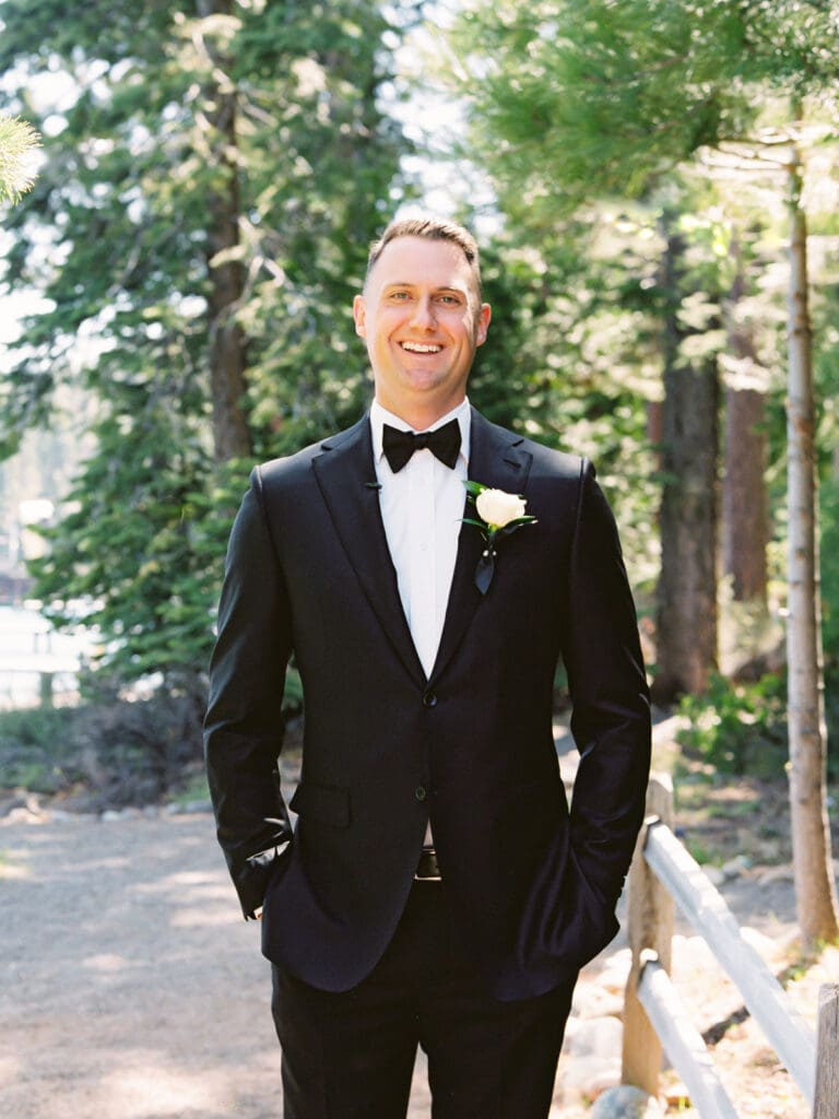 A stylish groom in a tuxedo poses for a portrait, showcasing a charming portrait at Gar Woods Lake Tahoe wedding.