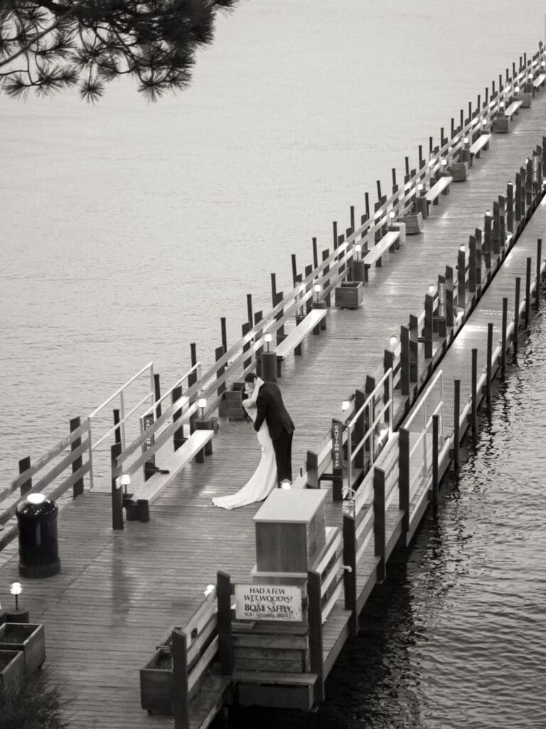 At sunset, a bride and groom kiss on the dock, celebrating their love during a beautiful Gar Woods Lake Tahoe wedding.