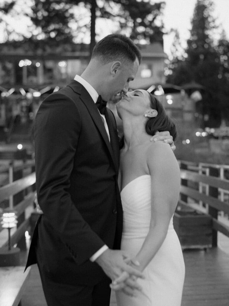 At sunset, a bride and groom kiss on the dock, celebrating their love during a beautiful Gar Woods Lake Tahoe wedding.