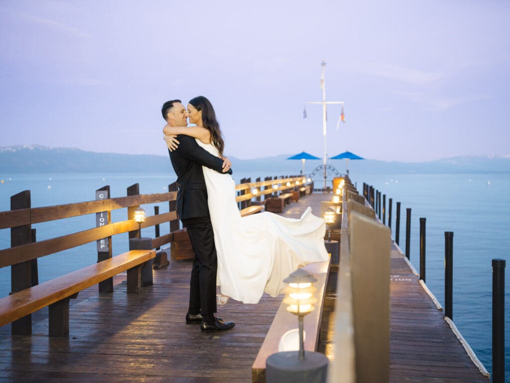 At sunset, a bride and groom kiss on the dock, celebrating their love during a beautiful Gar Woods Lake Tahoe wedding.