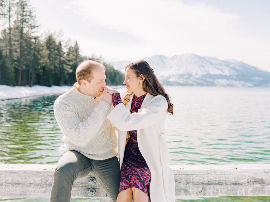 A photo of a couple on the dock cuddling and smiling at Lake Tahoe Winter Engagement Shoot