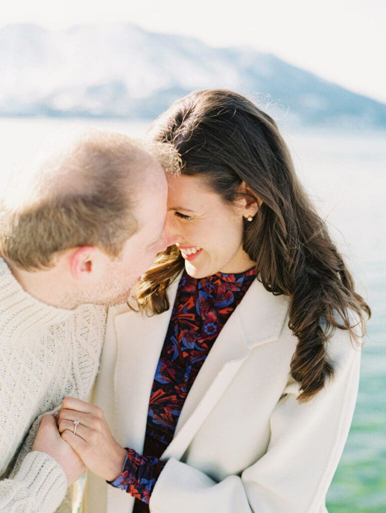 A photo of a couple on the dock cuddling and smiling at Lake Tahoe Winter Engagement Shoot