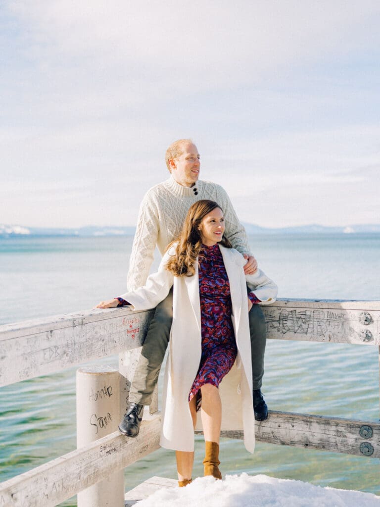 A photo of a couple on the dock cuddling and smiling at Lake Tahoe Winter Engagement Shoot