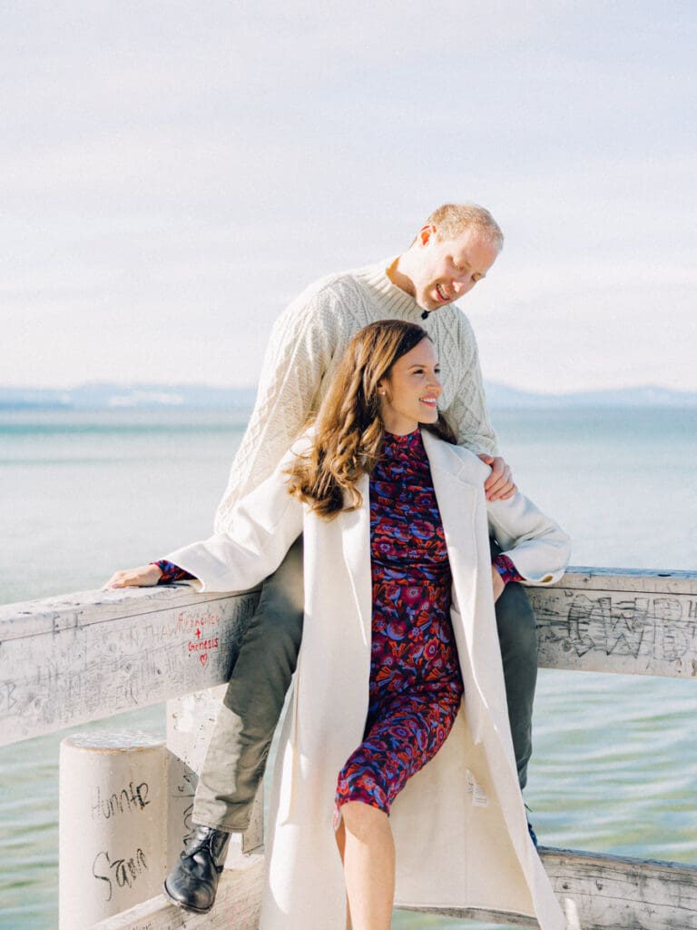 A photo of a couple on the dock smiling at Lake Tahoe Winter Engagement Shoot