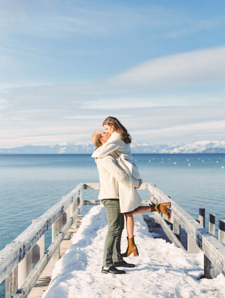 A photo of a couple on the dock kissing at Lake Tahoe Winter Engagement Shoot