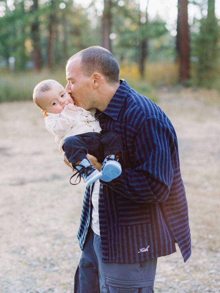 Dad and son poses together in a lush field surrounded by trees during their Lake Tahoe photo session.