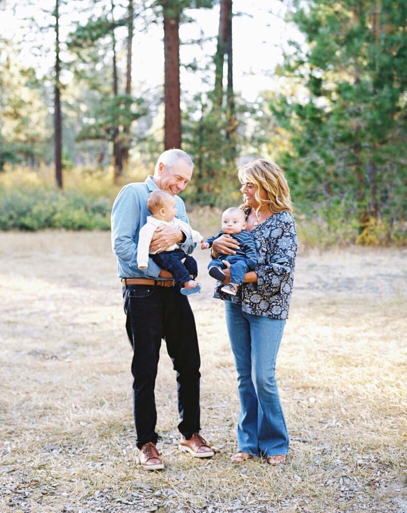 Grandparents and grandchildren poses together in a lush field surrounded by trees during their Lake Tahoe photo session.