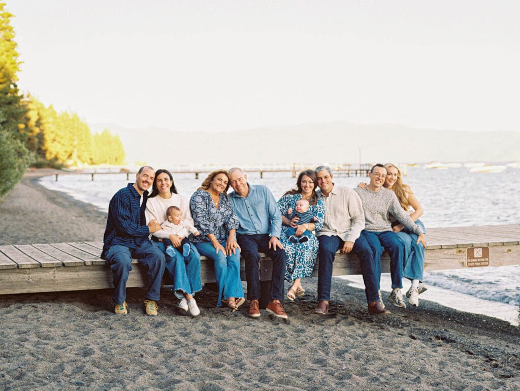 A cheerful family sitting on a dock at Lake Tahoe, enjoying a picturesque day by the lake in their portrait.