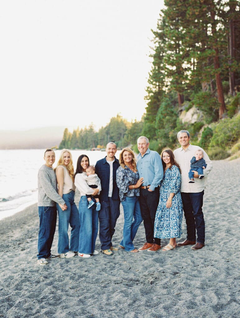 A cheerful family standing on the beach at Lake Tahoe, enjoying a picturesque day by the lake in their portrait.