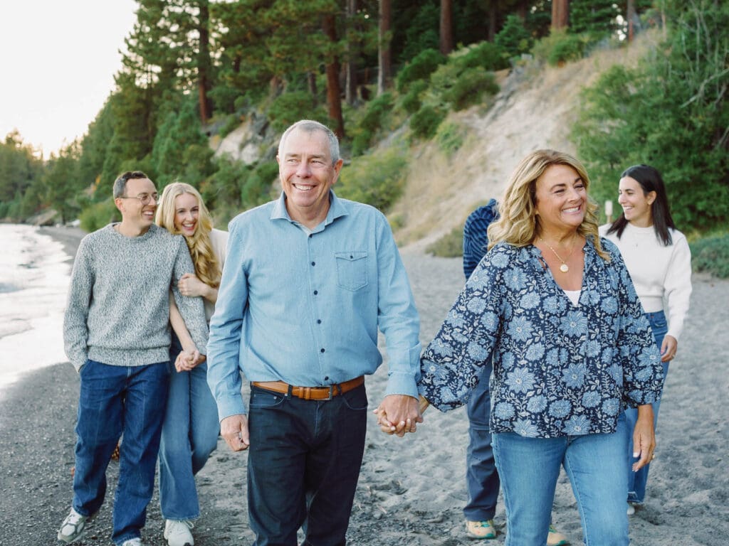 A cheerful family walking on the beach at Lake Tahoe, enjoying a picturesque day by the lake in their portrait.