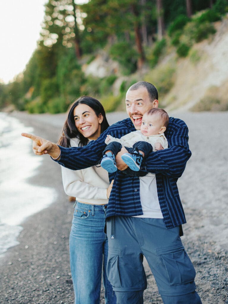  A joyful family poses on the Lake Tahoe beach, creating memories with their baby during a sunset.