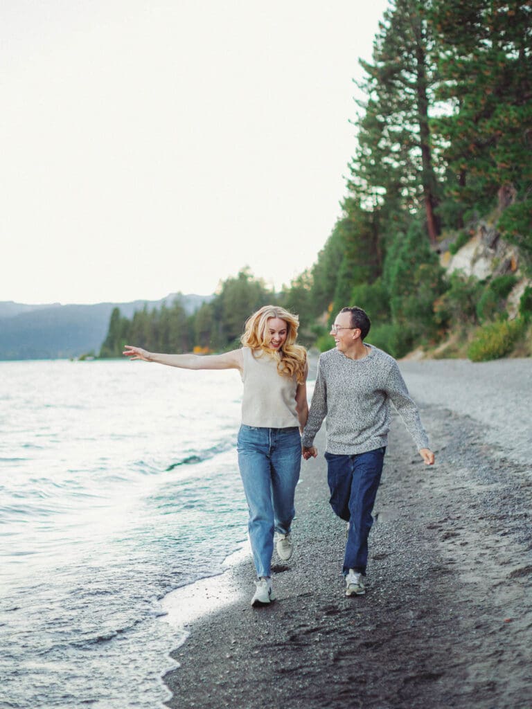 A couple running on the beach during a family photo session at Lake Tahoe, capturing a moment of love and connection.