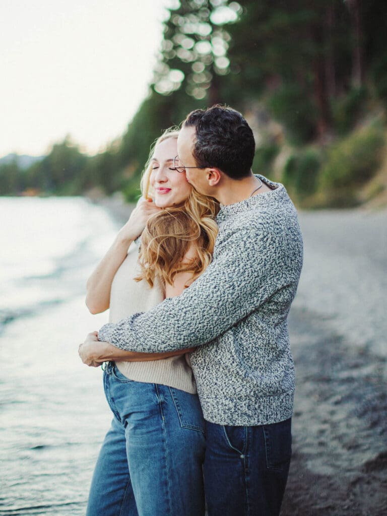 A couple embraces on the beach during a family photo session at Lake Tahoe, capturing a moment of love and connection.