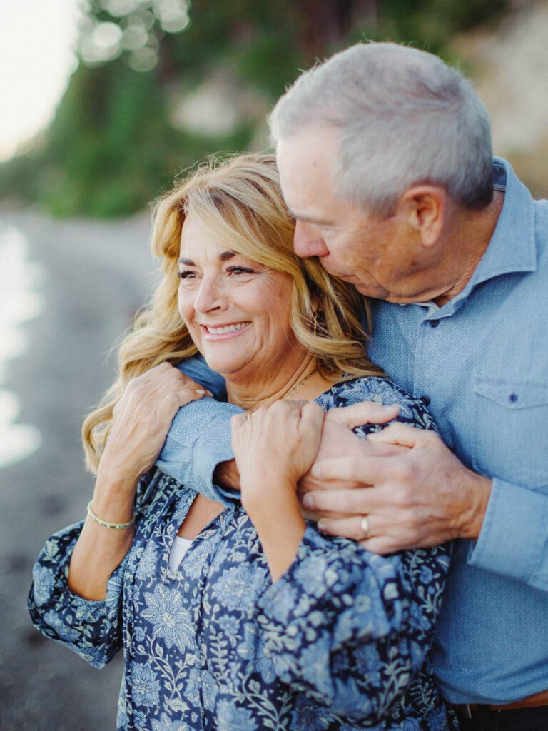 Grandparents embraces on the beach during a family photo session at Lake Tahoe, capturing a moment of love and connection.