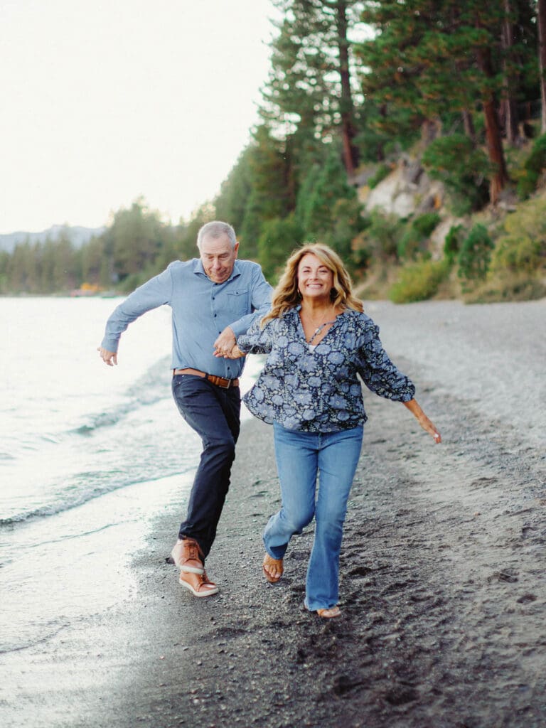 Grandparents running on the beach during a family photo session at Lake Tahoe, capturing a moment of love and connection.