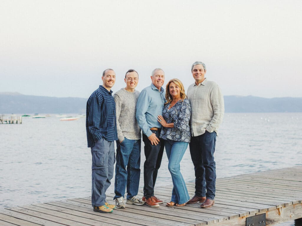 A cheerful family standing on a dock at Lake Tahoe, enjoying a picturesque day by the lake in their portrait.