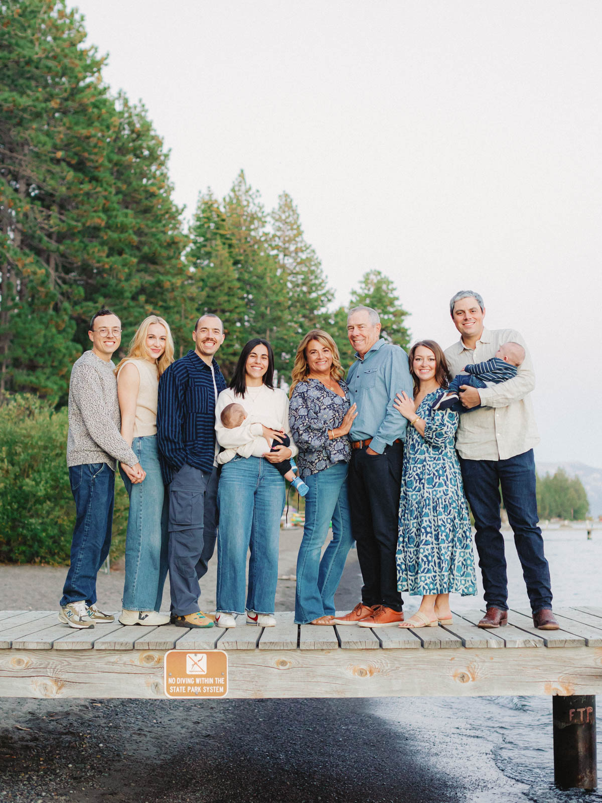 A cheerful family stands on a dock at Lake Tahoe, enjoying a picturesque day by the lake in their portrait.