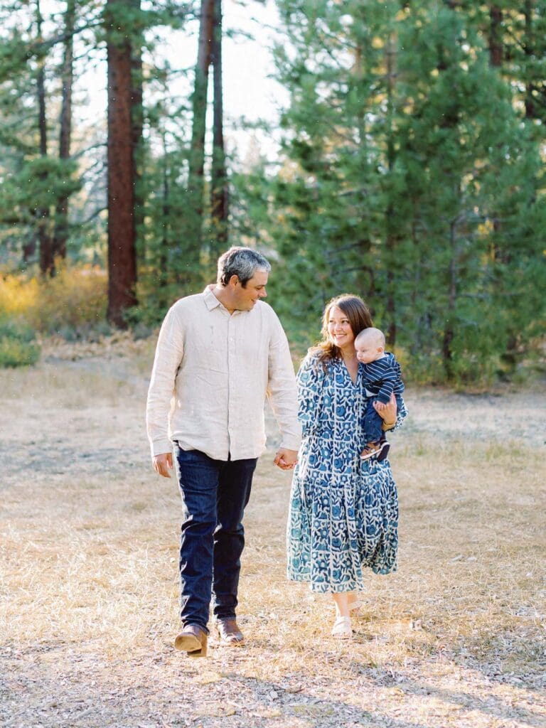 A family of three poses together in a lush field surrounded by trees during their Lake Tahoe photo session.