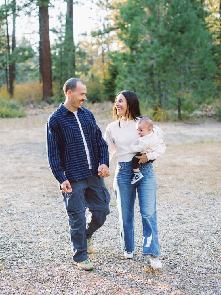 A family of three walking together in a lush field surrounded by trees during their Lake Tahoe photo session.