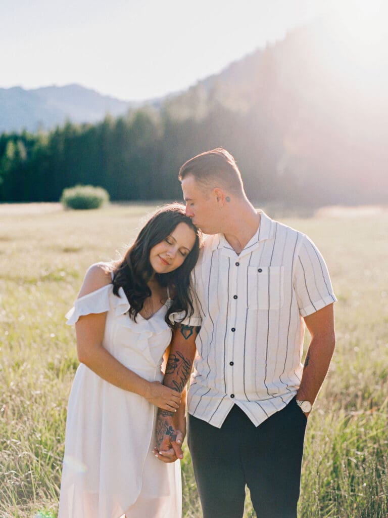 Engaged couple stands in a picturesque field, capturing a romantic moment during their Lake Tahoe engagement photo session.