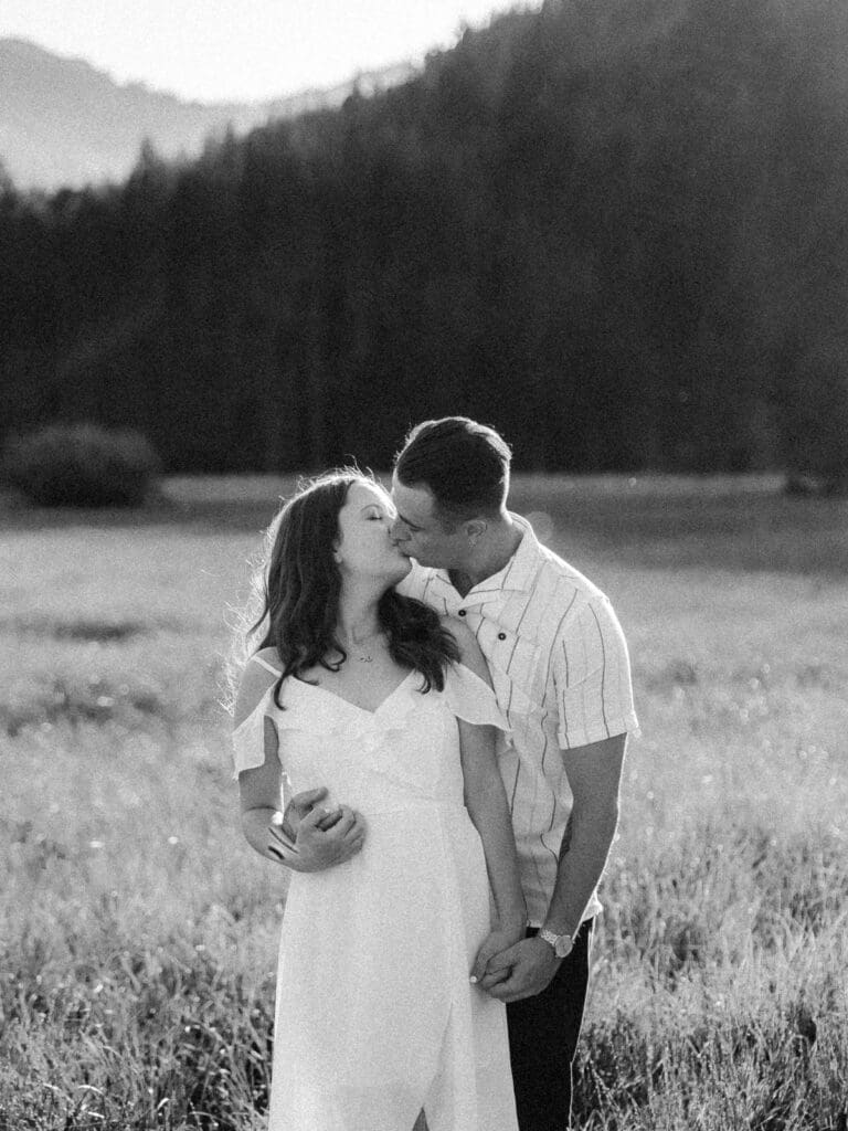 Engaged couple stands in a picturesque field, capturing a romantic moment during their Lake Tahoe engagement photo session.