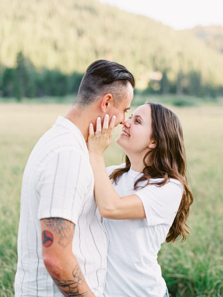 A couple kisses at a mountain field during their Lake Tahoe engagement photo session.