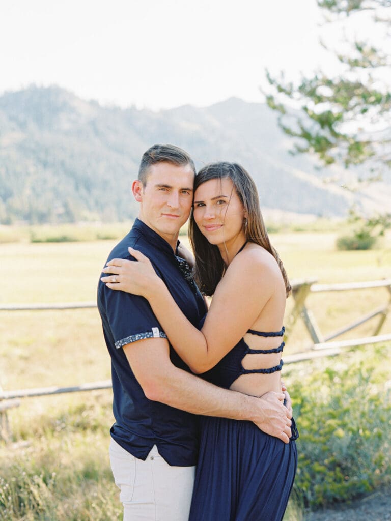 A couple embraces in a picturesque alpine meadow, surrounded by the stunning Lake Tahoe mountains.