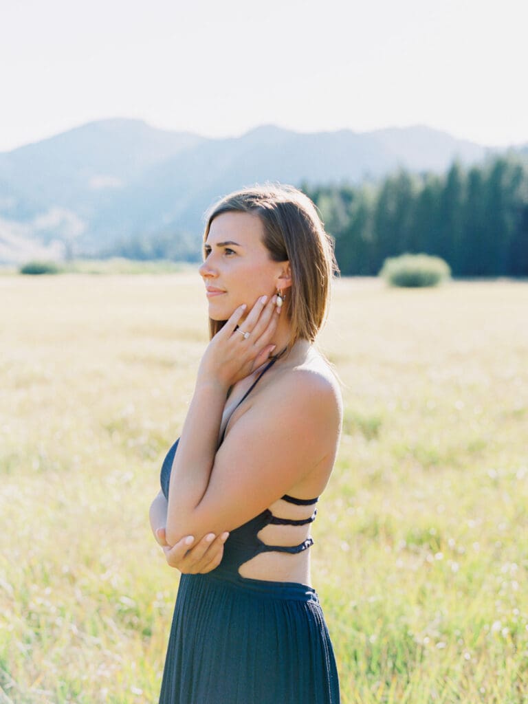 An engaged woman in a blue dress is captured in a field, with the majestic Lake Tahoe mountains providing a scenic backdrop.