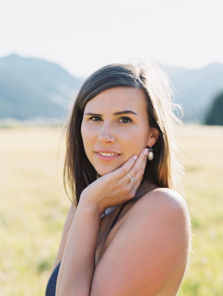 An engaged woman in a blue dress is captured in a field, with the majestic Lake Tahoe mountains providing a scenic backdrop.