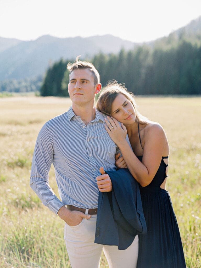 A couple poses in a scenic field, framed by the breathtaking Lake Tahoe mountains during their engagement photography session.