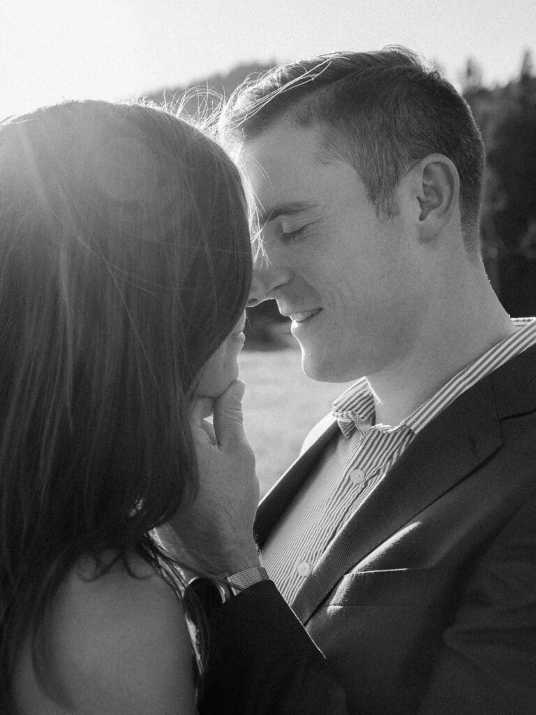 A couple shares a moment in a picturesque field, with the beautiful Lake Tahoe mountains serving as a backdrop for their engagement.