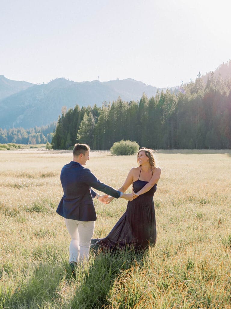 A couple dances in a picturesque field, with the beautiful Lake Tahoe mountains serving as a backdrop for their engagement.