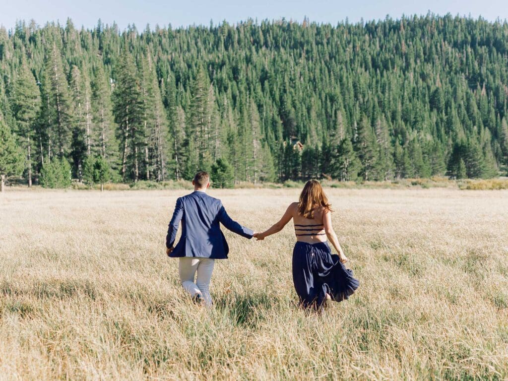 A couple running in a picturesque alpine meadow, surrounded by the stunning Lake Tahoe mountains.