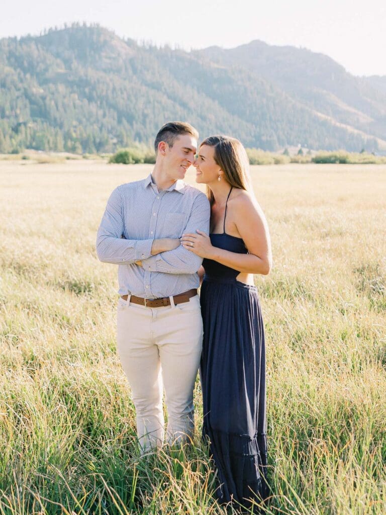 A couple embraces in a picturesque alpine meadow, surrounded by the stunning Lake Tahoe mountains.