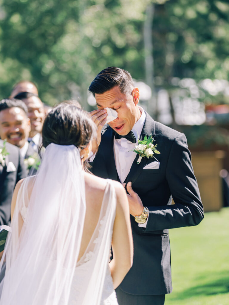 Groom cries at wedding ceremony at Tannenbaum Lodge, set against the breathtaking backdrop of Lake Tahoe's mountains.