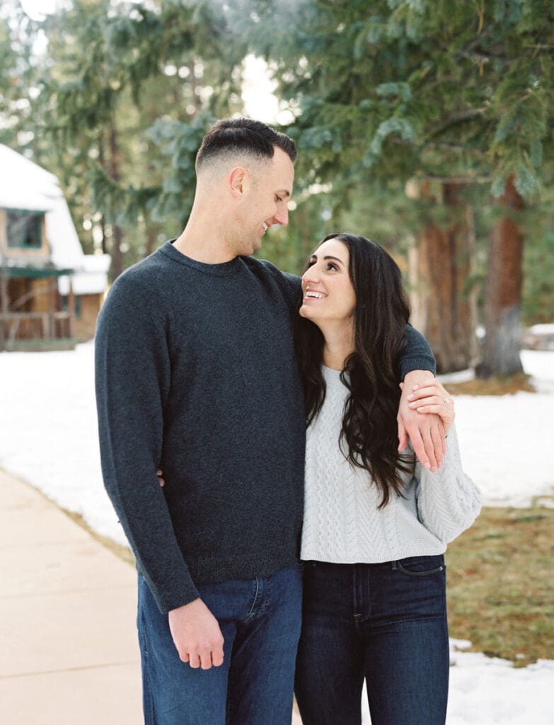 A couple embraces in a snowy landscape during their engagement session in Lake Tahoe, surrounded by serene winter scenery.