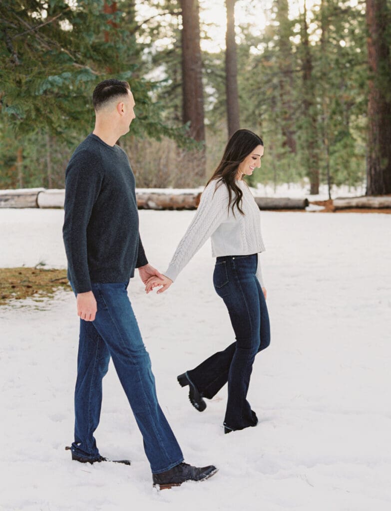 A couple walking in a snowy landscape during their engagement session in Lake Tahoe, surrounded by serene winter scenery.