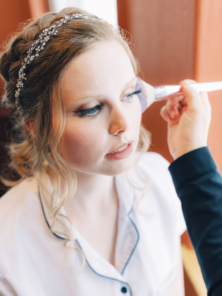 Bride putting makeup on portraits at Cozy Lake Tahoe Cabin Winter Wedding