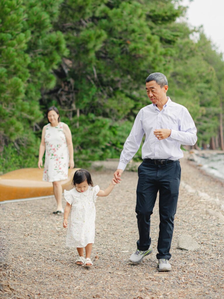 Grandparents and granddaughter poses together for a photo on the beach during their photography session in South Lake Tahoe.