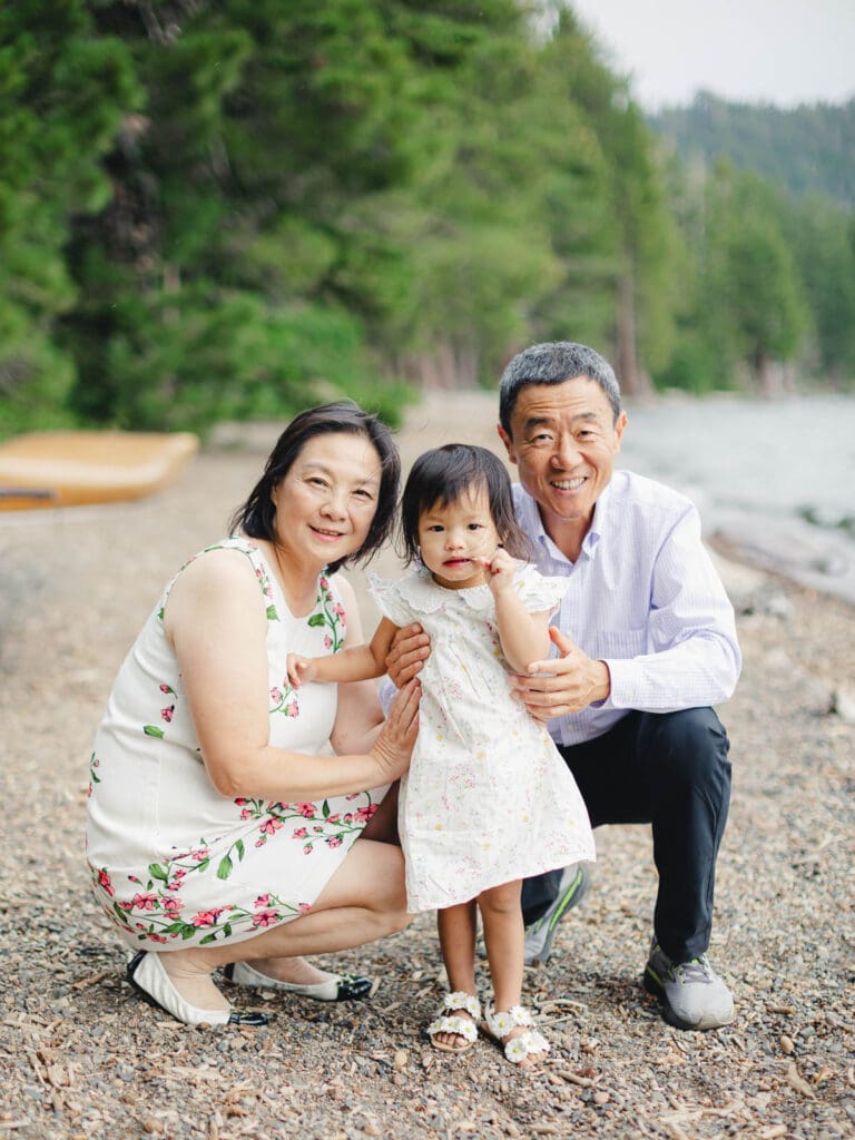 Grandparents and granddaughter poses together for a photo on the beach during their photography session in South Lake Tahoe.